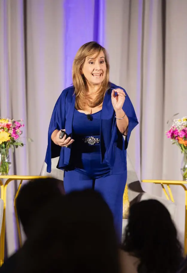 Monica DÃaz delivering an energetic keynote on stage about mindset shift and authentic leadership.